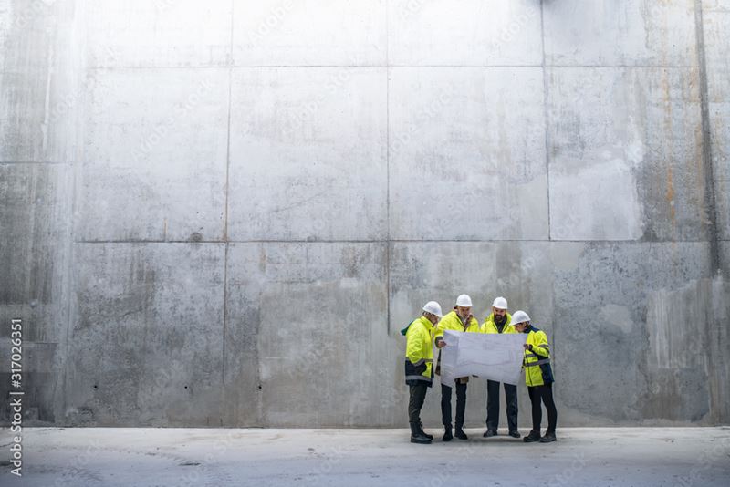 group of people looking at building plans wearing hardhats